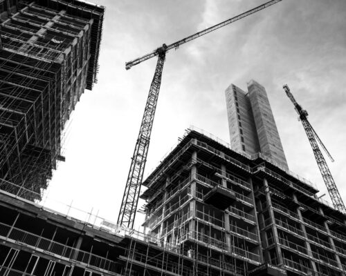 grayscale photo of crane in front of building